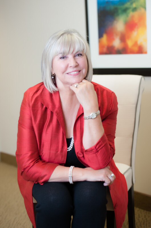 Kathlene Buchanan, a professional woman in a red blazer, smiling in Metro Offices setting.