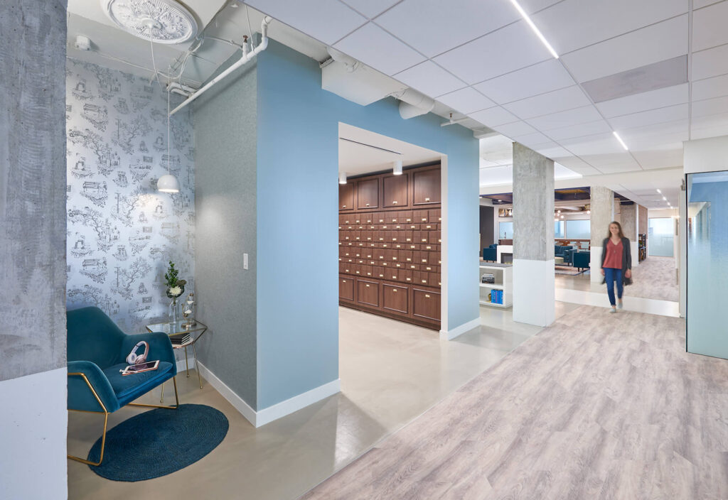 A woman is walking down a hallway in a coworking space.