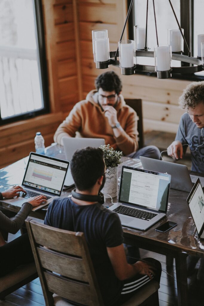 A group of people working at a shared workspace with laptops.