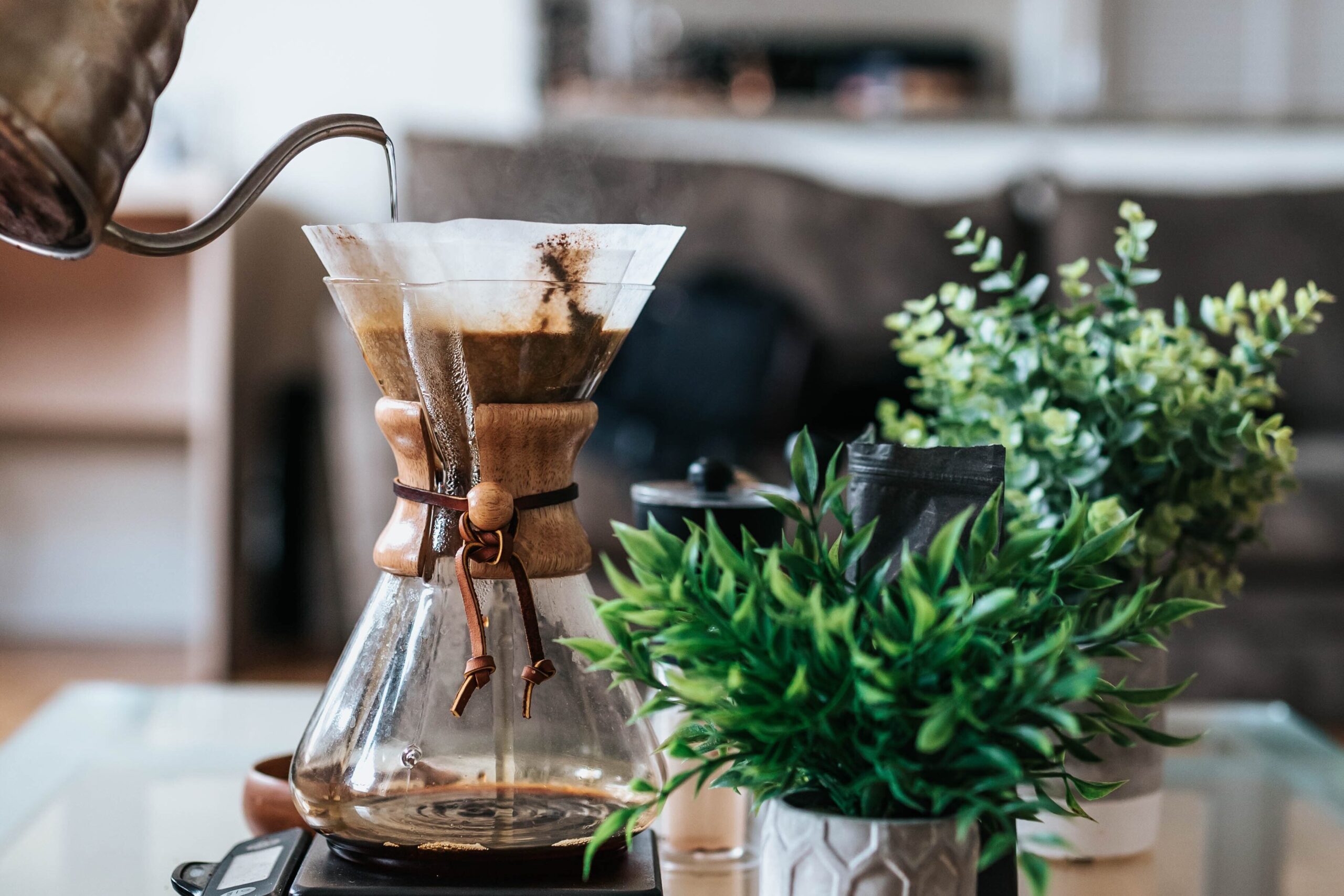 A person coworking at a shared workspace, pouring coffee into a glass coffee pot.