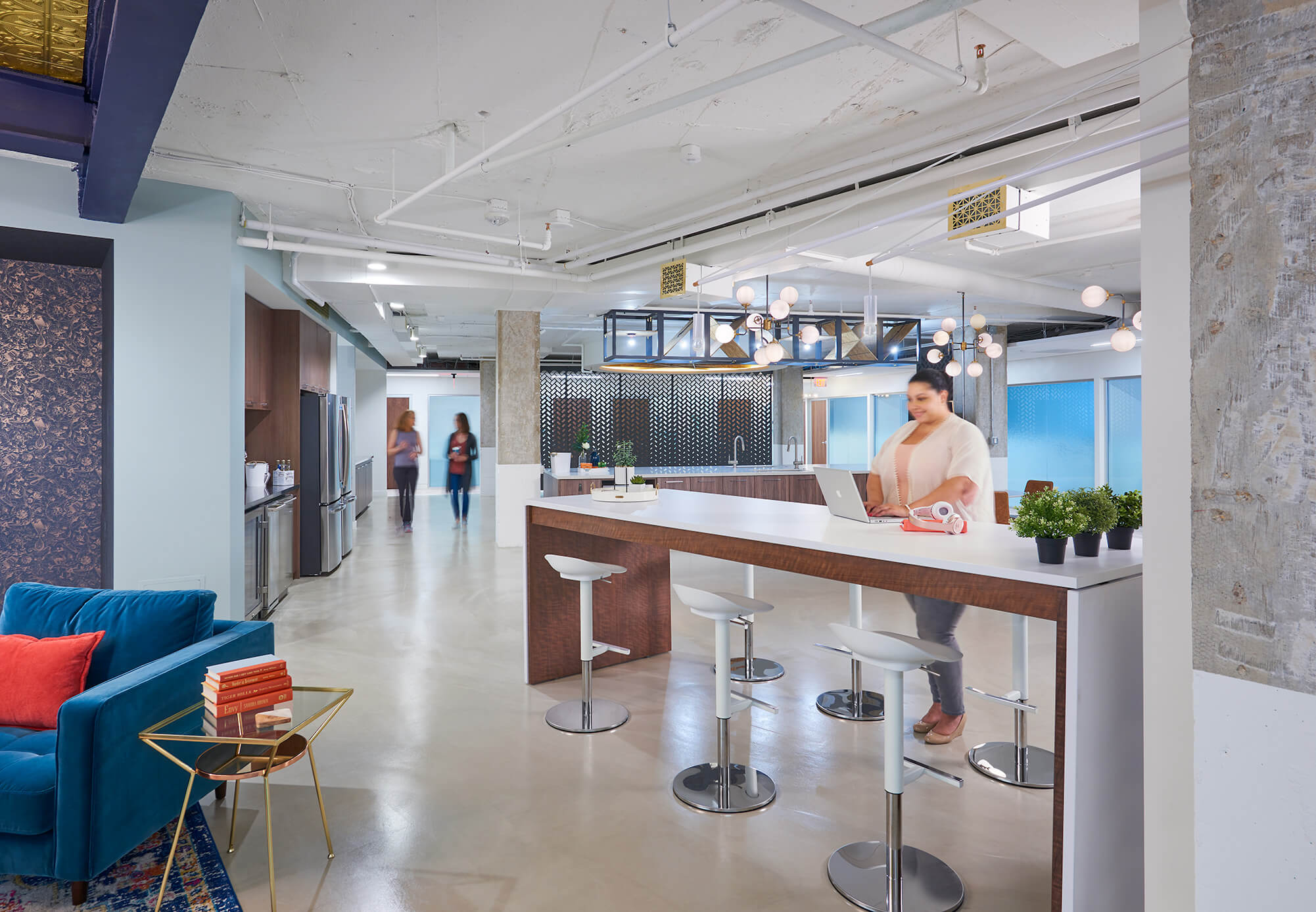 A woman sits at a coworking space bar.