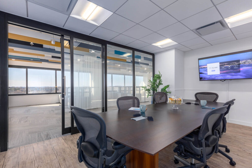 A meeting room with glass walls and a TV.