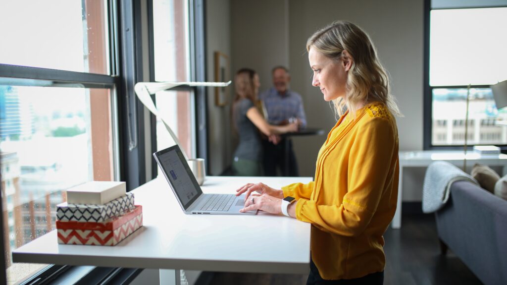 A woman using a laptop at a desk in a coworking space.