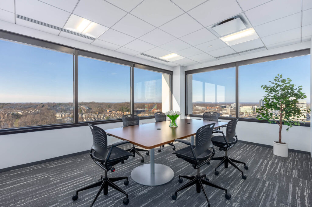 A meeting room with large windows overlooking a city.