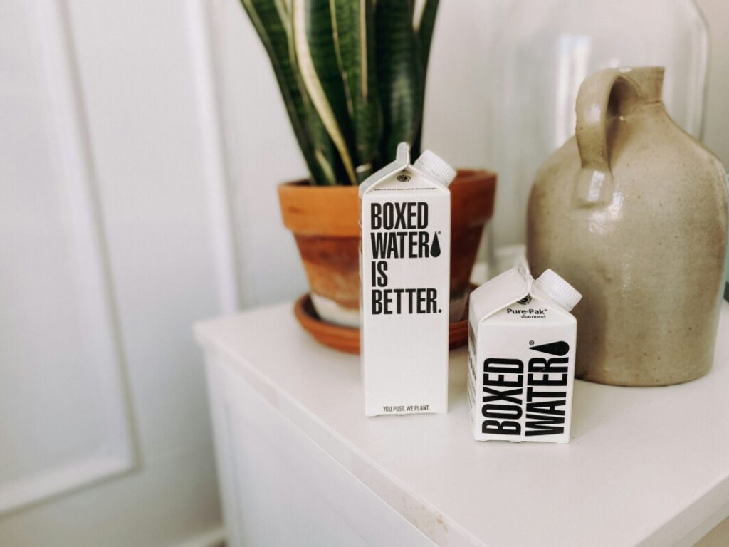 A box of baked goods sits on an eco-friendly table next to a plant in a private office.