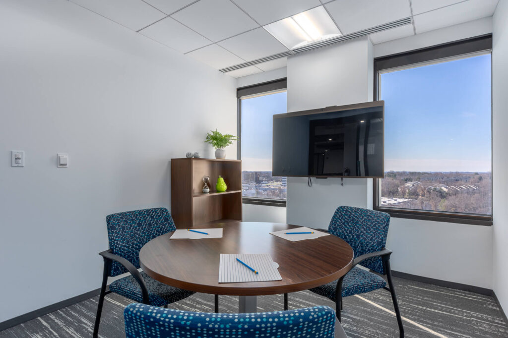 A meeting room with a table and chairs and a view of the city.