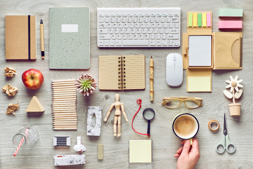 A woman's hand is laying out various eco-friendly office supplies on a wooden table in a private office.