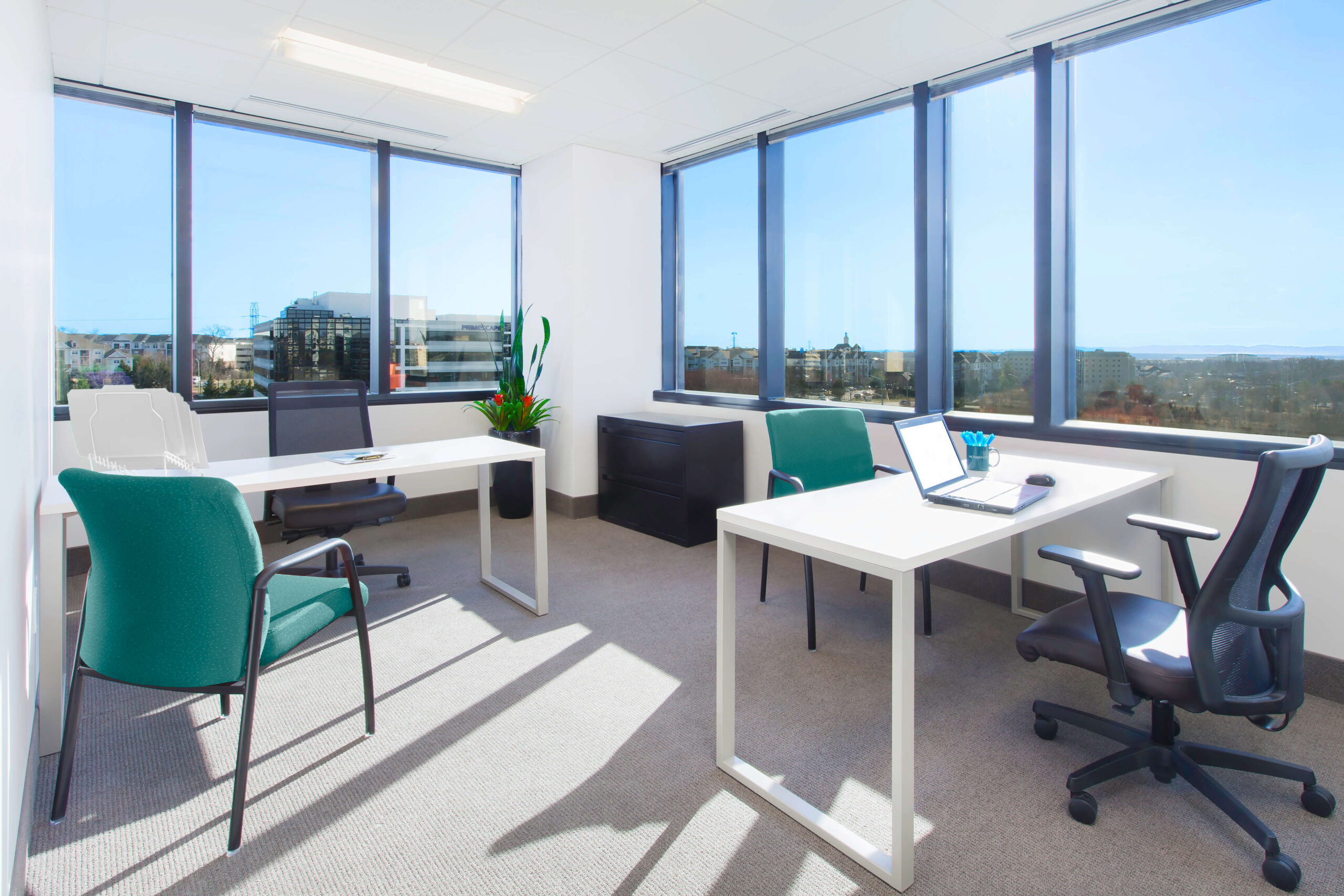 Office space with a desk and chairs offering a city view is available for rent.