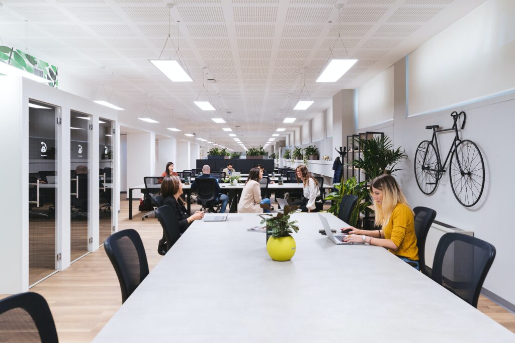 A group of people are sitting at a table in a coworking space office.